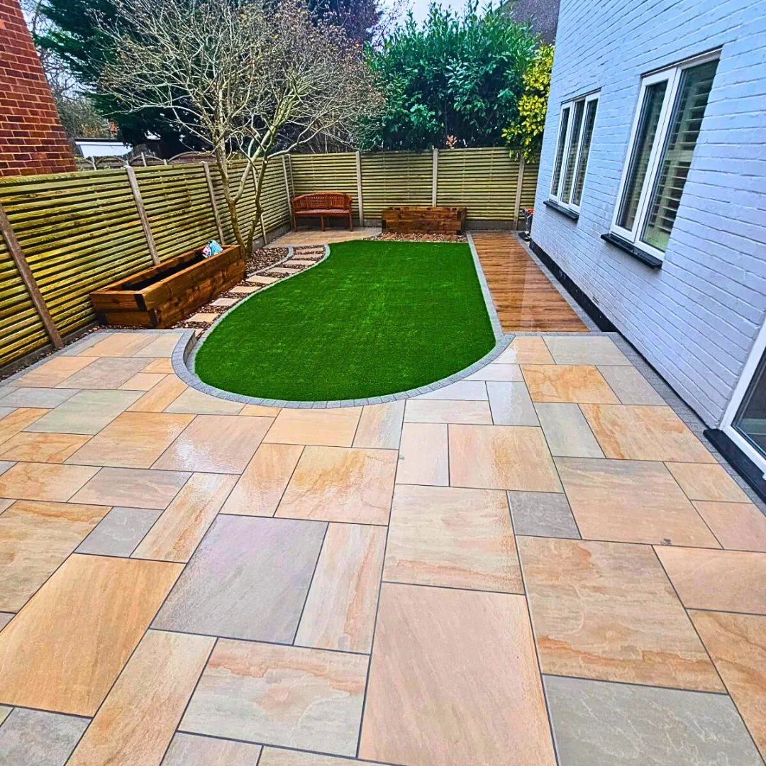 Warm sandstone patio surrounding a curved lawn and raised planting beds